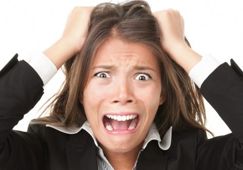Stress. Woman stressed is going crazy pulling her hair in frustration. Close-up of young businesswoman on white.